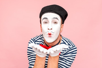 Man in striped sweater, white gloves sending air kiss