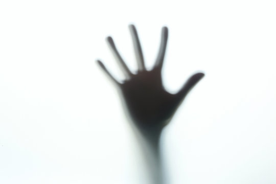 Hands silhouette behind a glass