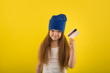 Beautiful caucasian girl posing on yellow background in studio holding in hands a credit card