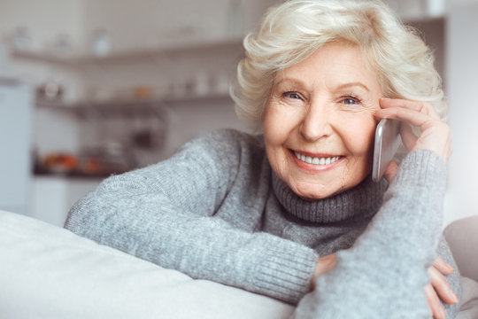 Portrait handsome grandmother in gray sweater talking on the phone