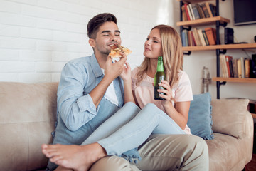 Young couple with beer and pizza at home