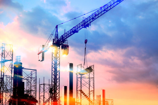 tower cranes at construction site with sun