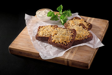 Bread with cheese. Fried garlic croutons with dill. On a wooden board. on a black background