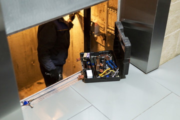 Specialist fixing or adjusting lift mechanism in elevator schaft. Regular repair, service and...