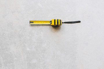Yellow used tape measure isolated on concrete floor with space for text