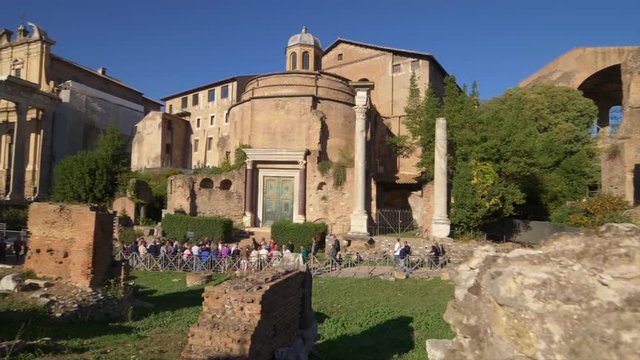 Tourist walk past the Temple of Romulus at the Roman Forum in Rome, Italy