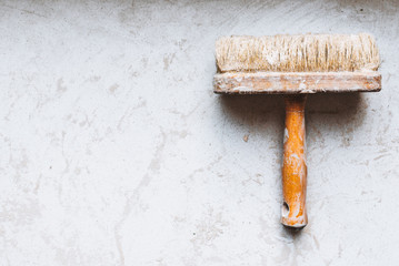 Big used wooden paint brush isolated on concrete floor with space for text