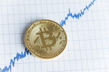 Gold bitcoin cryptocurrency coin top view on rising line graph stock market trading chart.