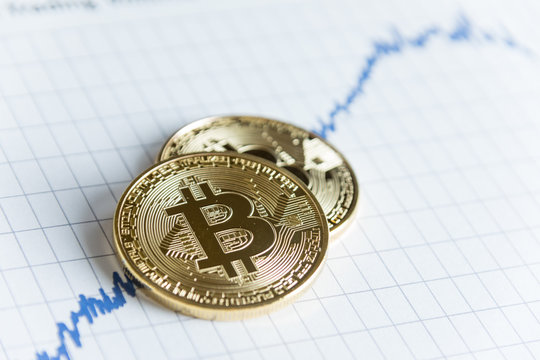 Pile of gold bitcoin cryptocurrency coin on rising line graph stock market trading chart with copy space.