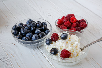 healhty breakfast or meal on white wooden table with cottage cheese and berries