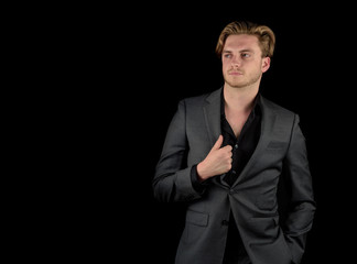 Male model in a classy dark suit isolated against a black background.