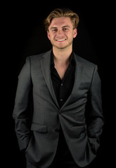 Male model in a classy dark suit isolated against a black background.