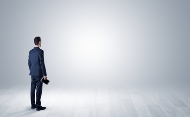 Obraz premium Man standing with his back in an empty room with object in his hand