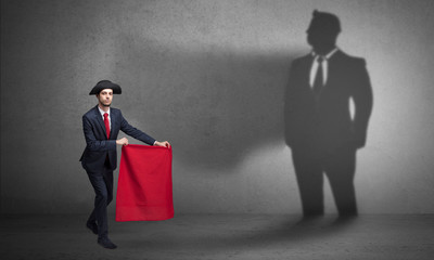 Businessman standing with red cloth on his hand and his shadow on the background
