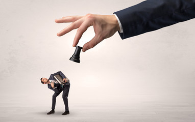 Big hand holding chessman and down little afraid businessman concept in a light space
