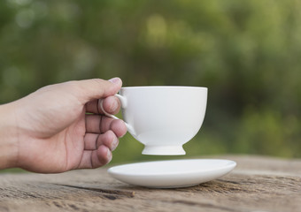 hands holding mug of hot drink that standing on wooden table