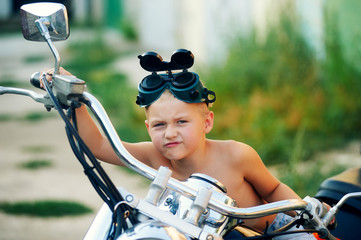 Obraz premium baby boy playing on his father's motorcycle . Dream to become a biker