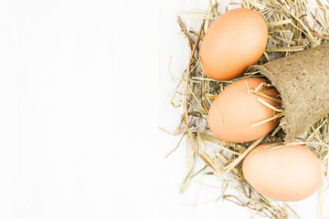 Chicken eggs and hay on a light background. Copy space for text