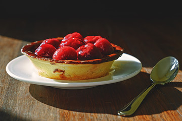 cherry dessert on white plate with spoon on wood table
