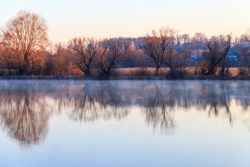 Naklejka na ściany i meble Peaceful lake in the mist. Fog over pond at morning