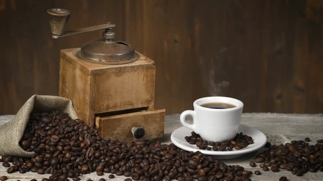 Vintage coffee grinder and cup of hot coffee on old wooden table - Toasted coffe beans 