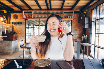 Smiling business women talking on smartphone holding coffee cup