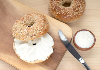  Bagel sesame with spread cream cheese close-up on a wooden cut board. 