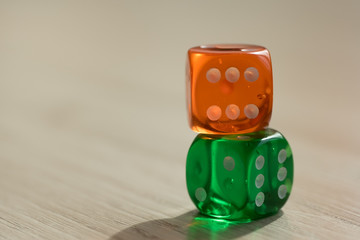 Colourful green and orange gambling dice on table