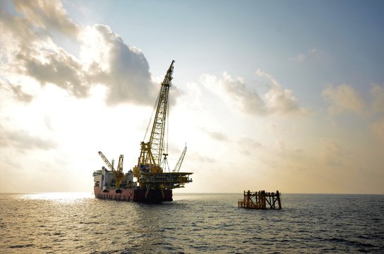 Derrick lay vessel is lifting platform topside to install on existing jacket.
