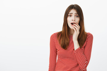 Girl watching tv drama, feeling worried about favorite character relationship. Portrait of anxious attractive female model in striped clothes, biting fingers and frowning, feeling guilty or nervous