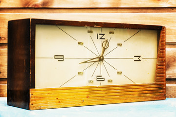 Old Rectangular clock on the background of wooden wall
