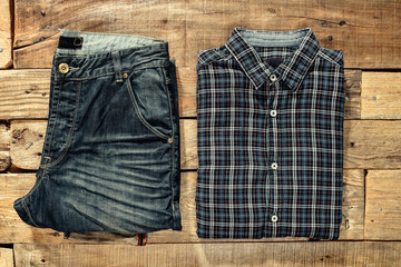 Checkered shirt and jeans on the wooden floor. Top view. Flat lay.