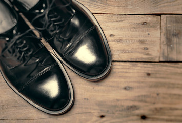 Fototapeta na wymiar Classic black men's shoes on the wooden floor. Top view. Flat lay.