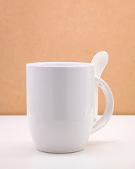 White coffee mug and spoon on backdrops. Ceramic tea cup for your design.