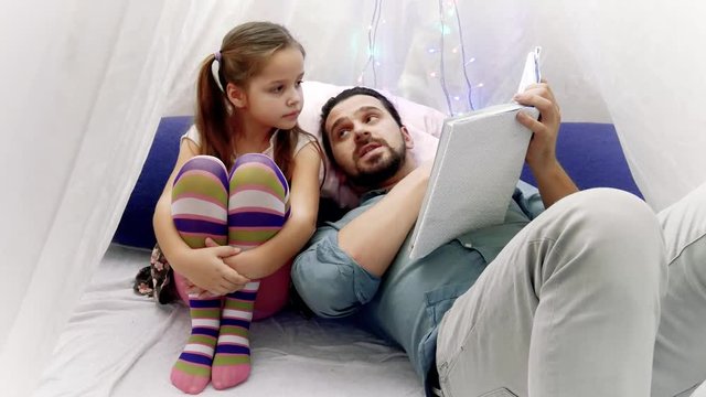 little girl and her father reading a book together