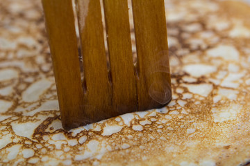 close-up cooking pancakes in a frying pan with a wooden stick