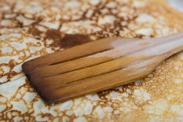 close-up cooking pancakes in a frying pan with a wooden stick
