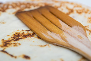 Fototapeta na wymiar close-up cooking pancakes in a frying pan with a wooden stick
