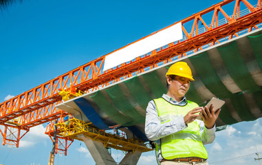 Male Engineer using tablet computer at constructions site for express way project,