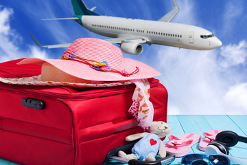 Travel concept with big red travel bag and accessory for trip,blue sky and airplane background.