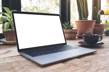 Fototapeta premium Top view mockup image of hands using and typing on laptop with blank white desktop screen on vintage wooden table in cafe