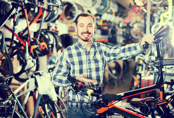 Fototapeta na wymiar man checks bicycle handlebar in shop when choosing bike
