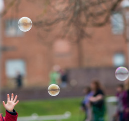childs hand reaches out to bubbles with blurred background representing coronavirus molecules
