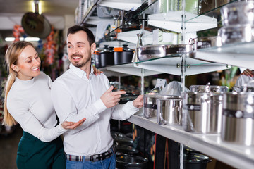 Young couple choosing new saucepan in dinnerware store