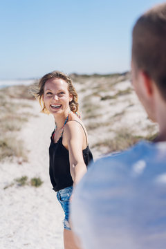 Laughing young woman pulling her boyfriend