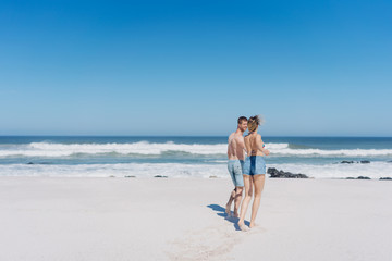 Young couple walking hand in hand across a beach