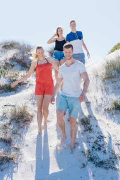 Group of happy friends walking on a sand dune