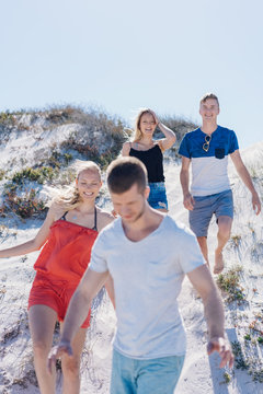 Group of young friends walking over a sand dune