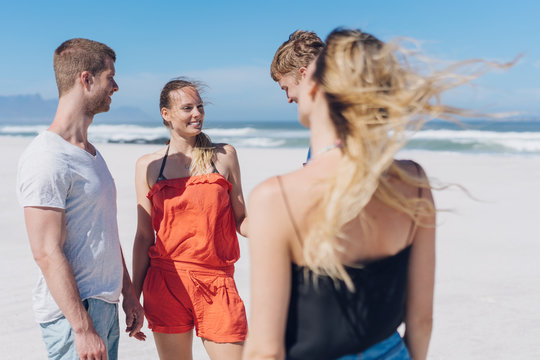 Two young couples chatting on a windblown beach