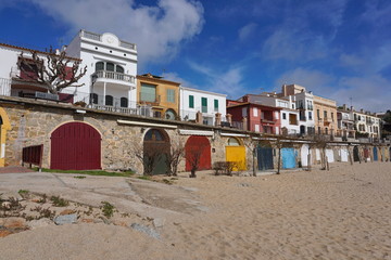 Colored wooden doors of boat storage on the beach and houses in the village of Calella de Palafrugell, Mediterranean, Spain, Costa Brava, Catalonia, Baix Emporda